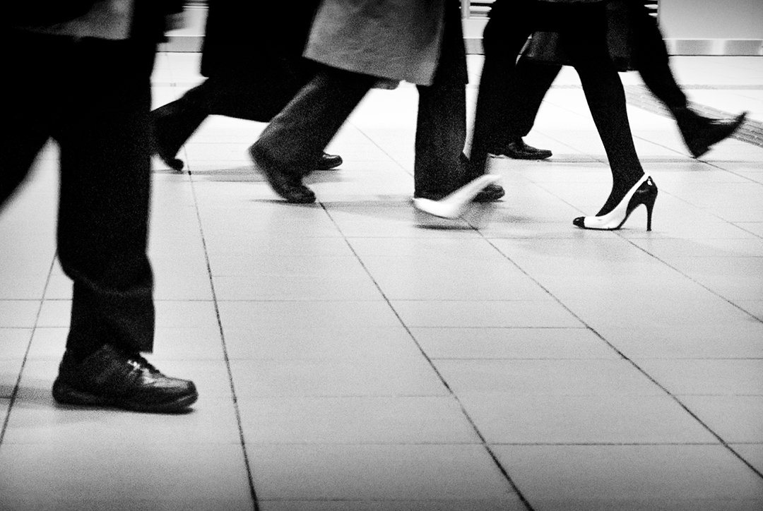 Several pedestrians crossing a tiled floor.